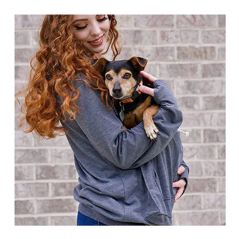 Woman wearing gray pet carrier hoodie holding small dog